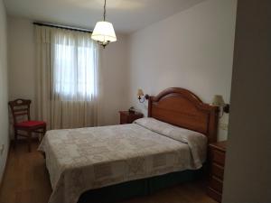 sypialnia z łóżkiem, krzesłem i oknem w obiekcie Coma de Alba Benasque w mieście Benasque