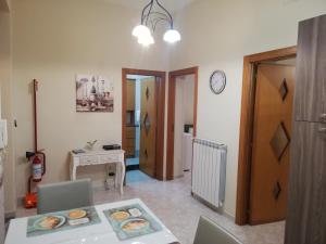 a living room with a table and a clock on the wall at Tortora House in Scafati