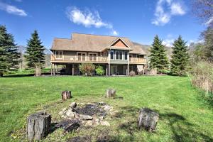 a large house on a green field with trees at House with Deck, Fire Pit - 15 Mins to Snowshoe! in Slaty Fork