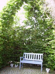 a white bench in front of a hedge with two birds at Ferienhaus-Weitblick in Wohlau