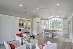 a living room with white furniture and a kitchen at Contemporary Tacoma Cottage with Deck and Pond! in Tacoma