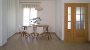 a dining room table with white chairs and a wooden door at Casa de la Jara 10 in Sanlúcar de Barrameda