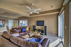 a living room with a leather couch and a ceiling fan at Waterfront Lake Ozark Condo with Deck and Pools in Lake Ozark