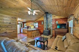 a living room with a leather couch and a kitchen at Secluded Cabin with Pond - 37 Mi to Gulf Coast! in Wiggins