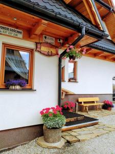 a patio with flowers and a picnic table in front of a house at Wynajem Pokoi Rancho in Ząb