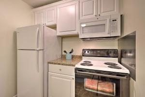 a kitchen with white cabinets and a stove and microwave at Gulfport Home with Deck and Grill, Walk to Beach! in Gulfport