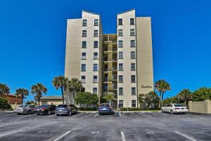 a large building with cars parked in a parking lot at Beachfront New Smyrna Condo: 1 Mi to Flagler Ave in New Smyrna Beach