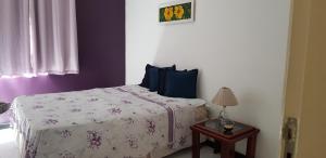 Apartamento Feliz في أراكاجو: غرفة نوم بسرير وطاولة مع مصباح