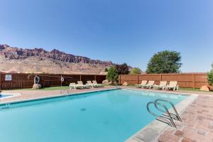 uma piscina com cadeiras e montanhas ao fundo em Rim Village Two-Bedroom em Moab