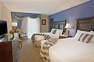 a hotel room with two beds and a television at Old Stone Inn Boutique Hotel in Niagara Falls