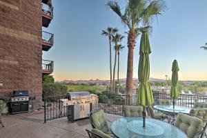 a patio with tables and chairs and a grill and palm trees at Queens Bay Resort Condo Walk to Golf, Pool, Beach in Lake Havasu City