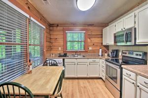 a kitchen with white cabinets and a wooden table at Cabin 18 Mi to Smoky Mountains National Park! in Clyde