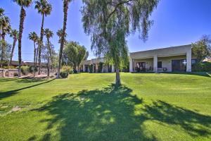 a building with palm trees in front of a yard at Cathedral City Condo on Golf Course with Patio! in Cathedral City