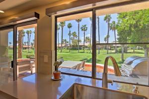 a kitchen with a view of a patio with palm trees at Luxury Remodeled Palm Desert Resort Condo! in Palm Desert