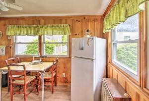 a kitchen with a white refrigerator and a table at Beachfront Sebago Cottage with Deck and Grill! in North Sebago