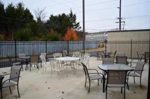 eine Terrasse mit Tischen, Stühlen und einem Zaun in der Unterkunft Baymont by Wyndham Fayetteville in Fayetteville