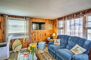 a living room with a blue couch and wooden walls at Cozy Hampton Cottage - Walk to Beaches and Marina! in Hampton