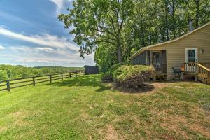 a house with a fence next to a yard at Cozy Rixeyville Cottage with Deck, Grill, and Stabling in Remington
