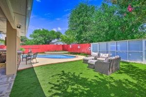 a backyard with a pool and a red fence at San Antonio Oasis with Hot Tub, Pool and Outdoor Bar! in San Antonio