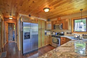 La cuisine est équipée d'armoires en bois et d'un réfrigérateur en acier inoxydable. dans l'établissement Quiet Adirondack Cabin on Private Lake!, à Glenfield