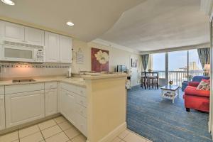 une cuisine avec des placards blancs et un salon dans l'établissement Daytona Beachfront Condo with Ocean View, à Daytona Beach