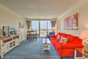 a living room with a red couch and a tv at Daytona Beachfront Condo with Ocean View in Daytona Beach
