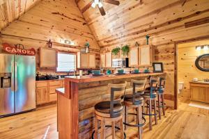 a log cabin kitchen with a bar and stools at Broken Bow Cabin with Deck on Mountain Fork River! in Broken Bow