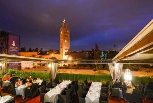 un gruppo di persone sedute al ristorante di notte di Hotel Islane a Marrakech
