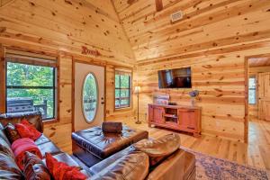 a living room with a couch and a tv in a log cabin at Broken Bow Cabin with Deck on Mountain Fork River! in Broken Bow