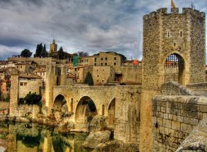 un antiguo edificio con un puente y un castillo en Apartaments del Llierca, en Sant Jaume de Llierca