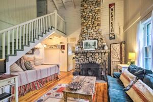 a living room with a couch and a stone fireplace at Saranac Lake Cabin with Beach Access in Lake Clear