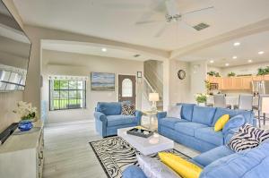 a living room with blue couches and a kitchen at Disney Villa with Game Room and Pool - 10 Mi to Parks! in Orlando