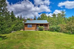 a log cabin on top of a grassy hill at Jacksonville Cabin with Wraparound Deck and Views in Jacksonville
