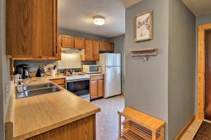 uma cozinha com armários de madeira e um frigorífico branco em Lincoln Condo with Pool Access - 6 Mi to Loon Mtn! em Lincoln