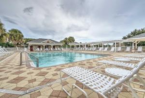 einen Pool mit weißen Liegestühlen und ein Resort in der Unterkunft The Villages Home on Golf Course Near Lake Sumter! in The Villages