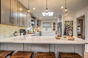 a kitchen with a large white counter with wooden stools at Modern Bungalow with Santa Fe Charm Less Than 2 Mi to Plaza in Santa Fe