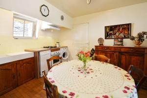 a kitchen with a table with a vase of flowers on it at Du côté de chez Marthe in La Cresse