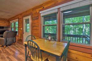 uma sala de jantar com uma mesa de madeira e 2 janelas em Clyde Cabin with Porch - Mins to Smoky Mountains em Clyde