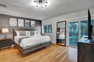 1 dormitorio con cama, TV y balcón en RA suites en Pompano Beach