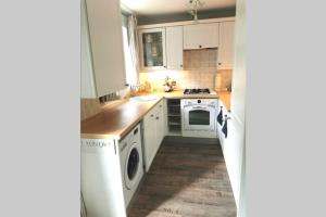 a kitchen with white cabinets and white appliances at Lavender House in Edwinstowe