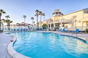 una piscina con sedie blu e un edificio di Corpus Christi Condo - Walk to Whitecap Beach! a Corpus Christi