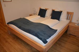 a large bed with white sheets and black pillows at Apart Pitztalurlaub in Wenns