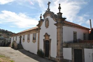 an old white building with an archway on a street at Casa de Sao Miguel Douro in Armamar