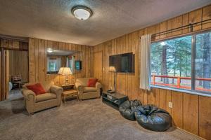 a living room with two chairs and a television at 2 Cozy Island Park Cabins with Near the Lake! in Island Park