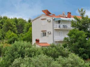 a white house on a hill with trees at Ljiljana Apartment in Okrug Gornji