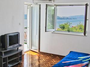 a living room with a tv and a large window at Ljiljana Apartment in Okrug Gornji