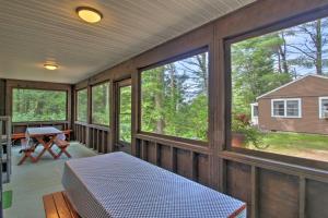 porche cubierto con cama y ventanas en Family Cabin with Beach Access on Panther Pond, en Raymond
