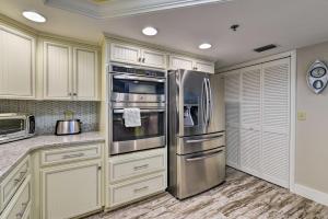 a kitchen with white cabinets and stainless steel appliances at Lavish Beachfront Condo with Balcony and Pool Access in New Smyrna Beach