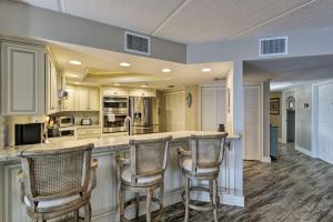 a kitchen with a counter with three bar stools at Lavish Beachfront Condo with Balcony and Pool Access in New Smyrna Beach