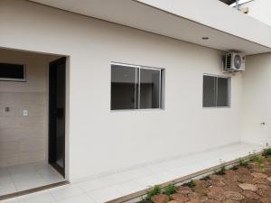um edifício branco com uma porta e janelas em Flat Genoveva em Tangará da Serra